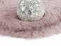 Un tapis en fourrure rose avec une boule de verre décorative.