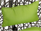 Un coussin vert sur une chaise en osier.