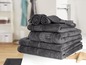 Une pile de serviettes de bain gris foncé dans une salle de bain.