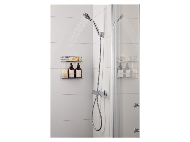 Douche avec douchette, étagère de douche avec flacons et éponges dans une salle de bain carrelée blanche.