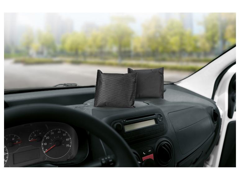 Deux coussins noirs absorbeurs d'humidité sur le tableau de bord d'une voiture.