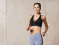 Une femme vêtue d'un soutien-gorge de sport noir et de leggings bleus en train de faire de l'exercice.