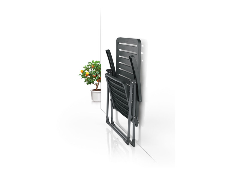 Une chaise pliante noire contre un mur blanc.