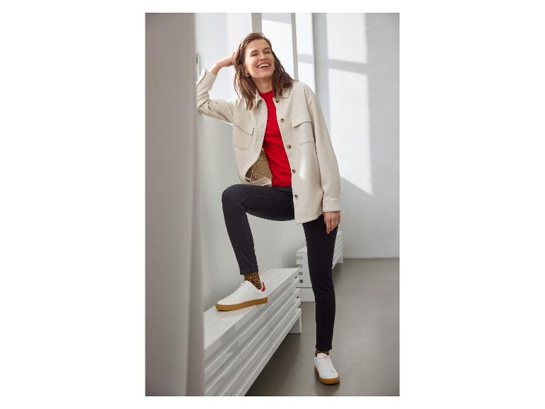 Femme en surchemise beige, haut rouge, jean noir et baskets blanches avec chaussettes léopard.