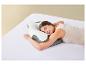 Femme dormant sur le côté sur un oreiller ergonomique sur des draps blancs.