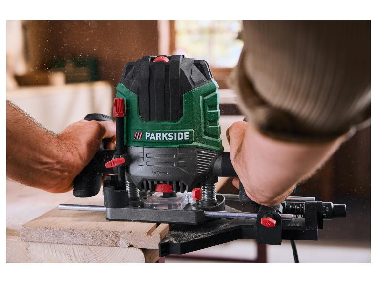 Un homme utilise une défonceuse pour travailler une pièce de bois, avec de la sciure en l'air.