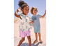 Deux enfants portant des vêtements d'été sur la plage, dont un t-shirt à coquillages et un t-shirt avec l'inscription « hello summer ».