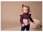 Une petite fille porte une veste en polaire rose et violette.