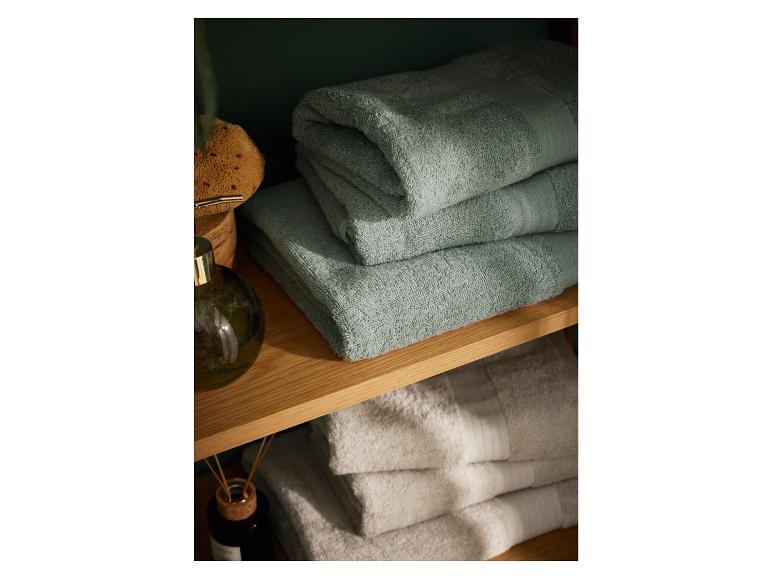 Serviettes de bain vert-de-gris empilées sur une étagère en bois.