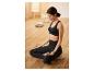 Une femme porte un soutien-gorge de sport noir et un legging pendant une séance de yoga.