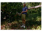 Homme en polo bleu et short vert dans une forêt.
