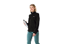 Femme souriante en veste polaire noire et pantalon de sport turquoise, tenant une gourde.