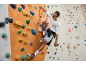 Homme escaladant un mur d'escalade avec un t-shirt à manches longues et un short de sport.