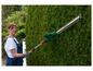 Une femme utilisant une taille-haie électrique Bosch pour tailler une haie.