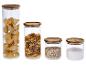 Quatre bocaux en verre avec couvercles en bois, contenant des pâtes, de l'avoine et du sel.