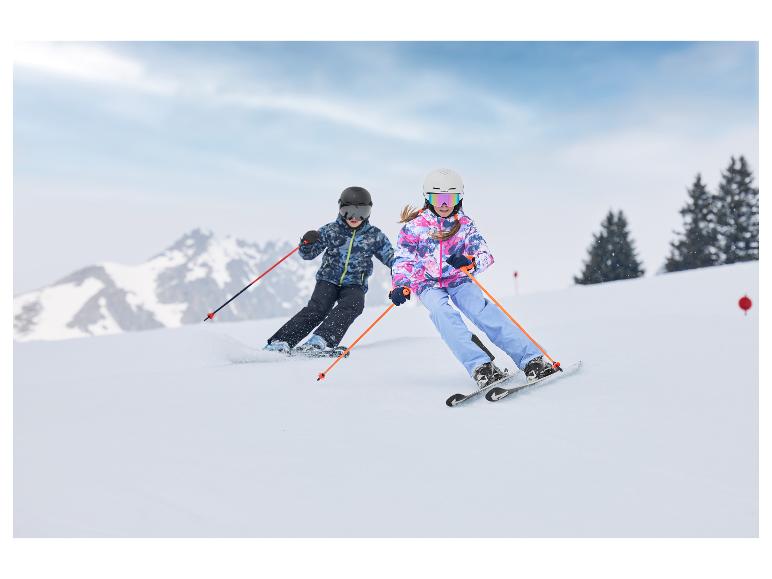 Enfants portant des vestes de ski CRIVIT skiant sur une piste enneigée.