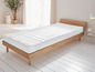 Un matelas blanc avec une texture ondulée sur un cadre de lit en bois.