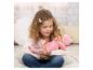 Une jeune fille en haut rose et jean tenant une poupée bébé en tenue rose.