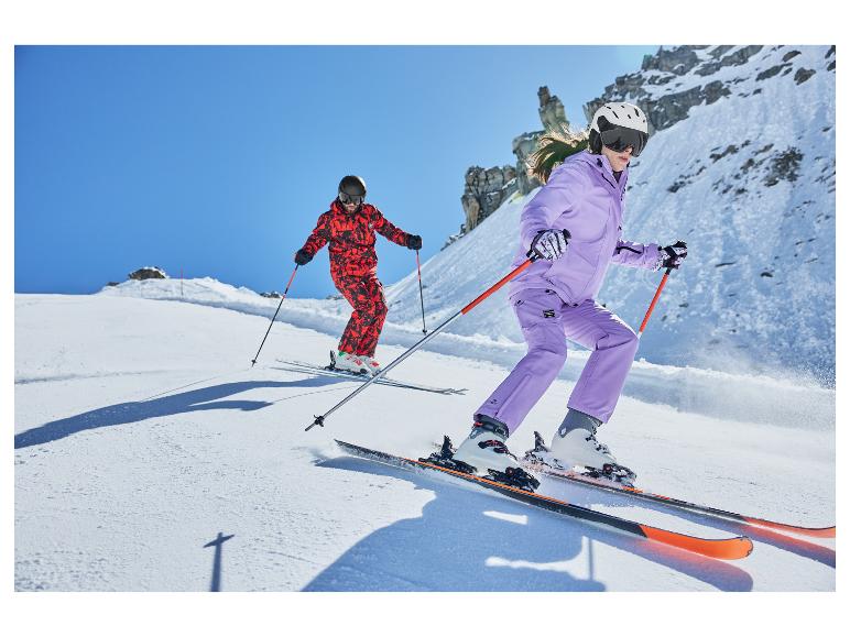 Deux skieurs en combinaisons de ski colorées et casques descendent une pente enneigée.