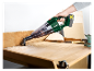 Une personne utilise un aspirateur sans fil Parkside pour nettoyer de la sciure sur une table en bois.