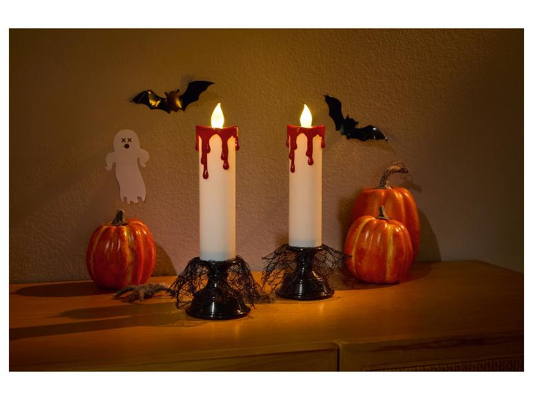 Décoration d'Halloween avec deux bougies dégoulinantes de sang, des citrouilles, des chauves-souris et un fantôme.