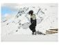 Un enfant avec un snowboard gravit une montagne enneigée.