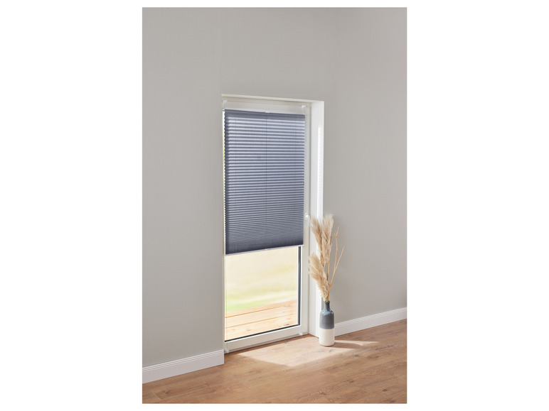 Un store plissé gris sur une porte avec un sol en bois.