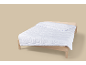 Couette blanche à motif ondulé sur un lit en bois.