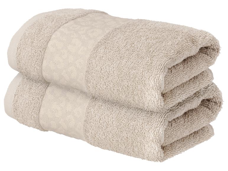 Deux serviettes beiges pliées avec motif, empilées l'une sur l'autre.