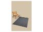 Tapis gris avec une chaise en bois et cannage sur fond beige.