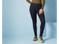 Une femme portant un jean skinny bleu foncé et des baskets beiges.