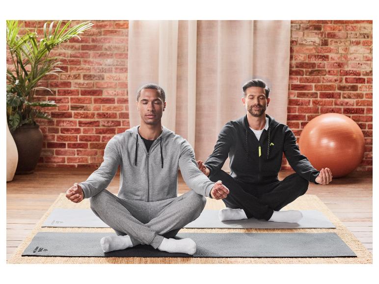 Deux hommes méditent en lotus sur des tapis de yoga.