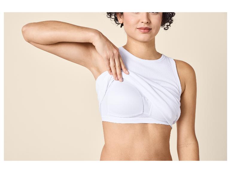 Femme en débardeur blanc révélant une brassière de sport blanche en dessous.