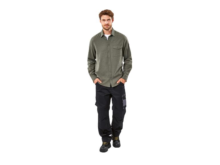 Homme en chemise verte et pantalon de travail noir