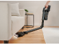 Aspirateur sans fil nettoyant la poussière sous le canapé du salon.