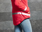 Une veste rose avec des bandes réfléchissantes, portée sur un jean.