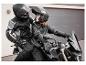 Un homme et une femme en tenue de moto et casques sur une moto.