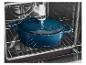 Cocotte en fonte bleue avec couvercle à l'intérieur d'un four sur une grille.