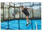 Joueur de padel sur le court, vêtu de vêtements de sport noirs, frappant la balle avec une raquette.