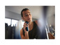 Un homme se rase avec un rasoir Philips.