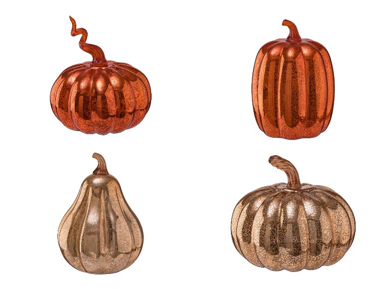 Quatre citrouilles décoratives en verre, deux orange et deux dorées.