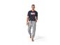 Un homme porte un pantalon de survêtement gris et un t-shirt noir avec le logo Marvel.