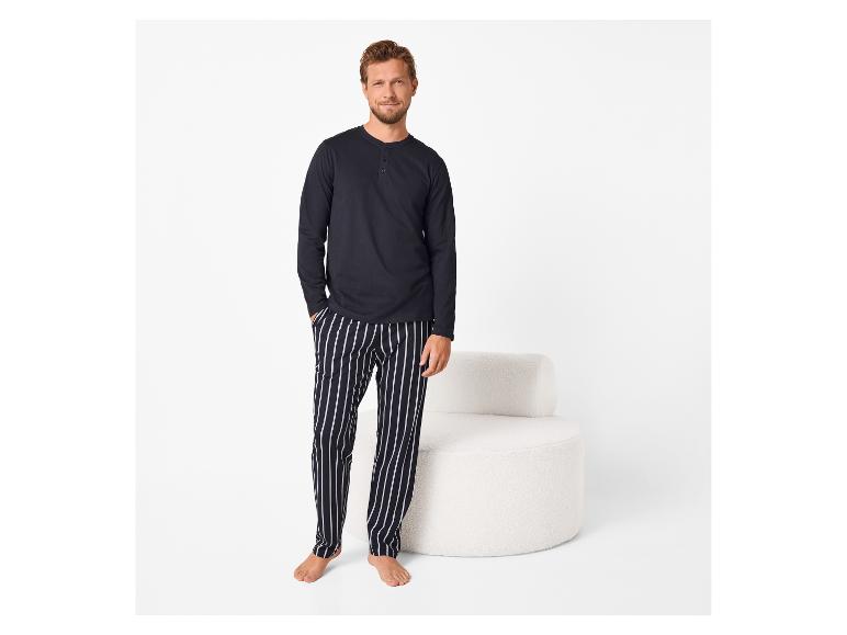 Homme en t-shirt à manches longues bleu marine et pantalon de pyjama rayé.