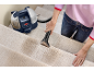 Nettoyeur de tapis portable sur un escalier nettoyé par une personne.