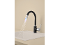 Robinet de cuisine noir avec bec flexible et lumière LED, projetant de l'eau dans un évier.