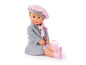 Une poupée avec un manteau gris et des chaussures roses.