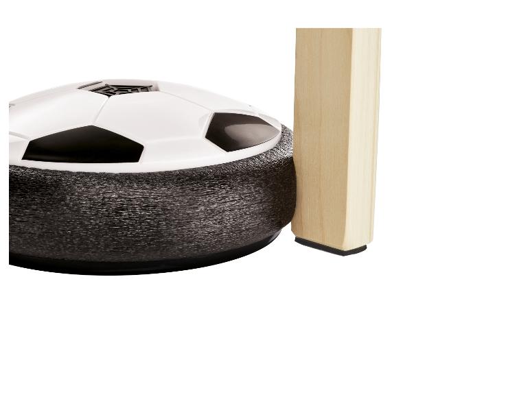 Ballon de football flottant avec pare-chocs souple, à côté d'un pied de table en bois.
