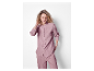 Une femme en pyjama rose clair avec une chemise à manches longues et un pantalon.