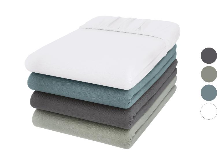 Pile de draps housses de différentes couleurs : blanc, bleu, gris foncé et vert clair.