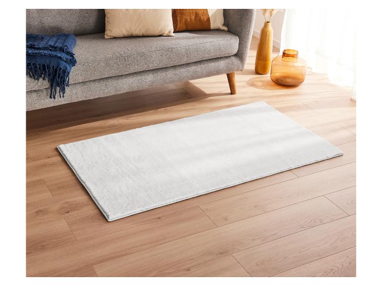 Un tapis blanc sur un sol en bois.